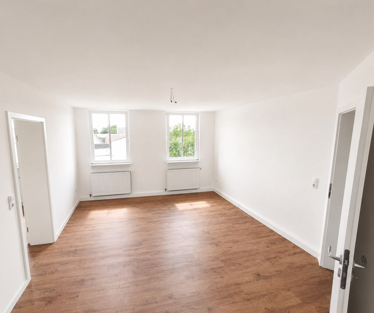 Heller Wohnraum mit zwei Fenstern und Holzfußboden